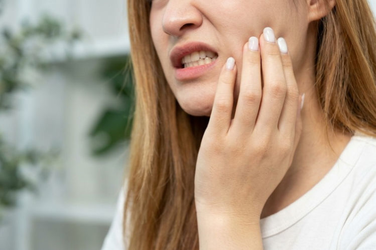 Woman holding her cheek in pain from clenching her teeth