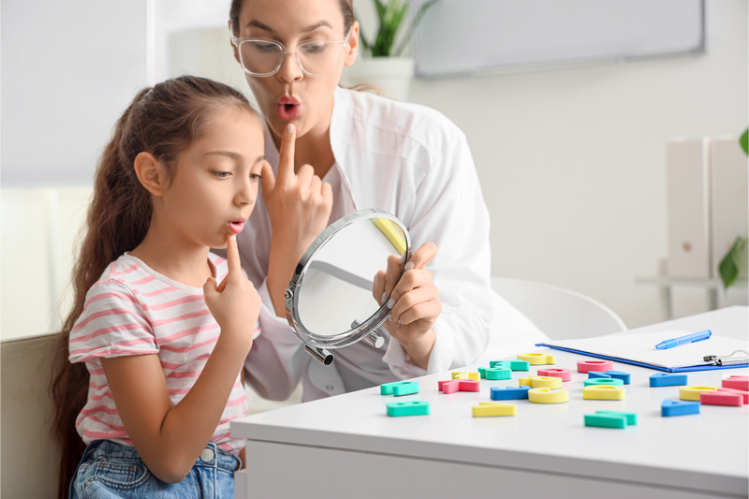 Speech therapist working with a young girl practicing speech at a table