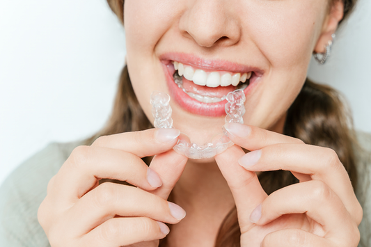 A close-up of a woman applying clear aligners.