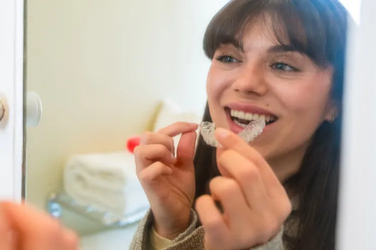  A girl looking in the mirror as she applies clear aligners.