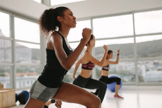 Women doing a lunge workout together in a bright fitness studio