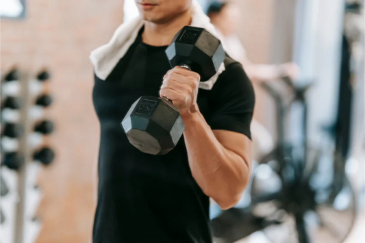 Man in a black t-shirt lifting a dumbbell at the gym