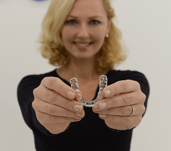 A woman holding Aligner32 clear aligners